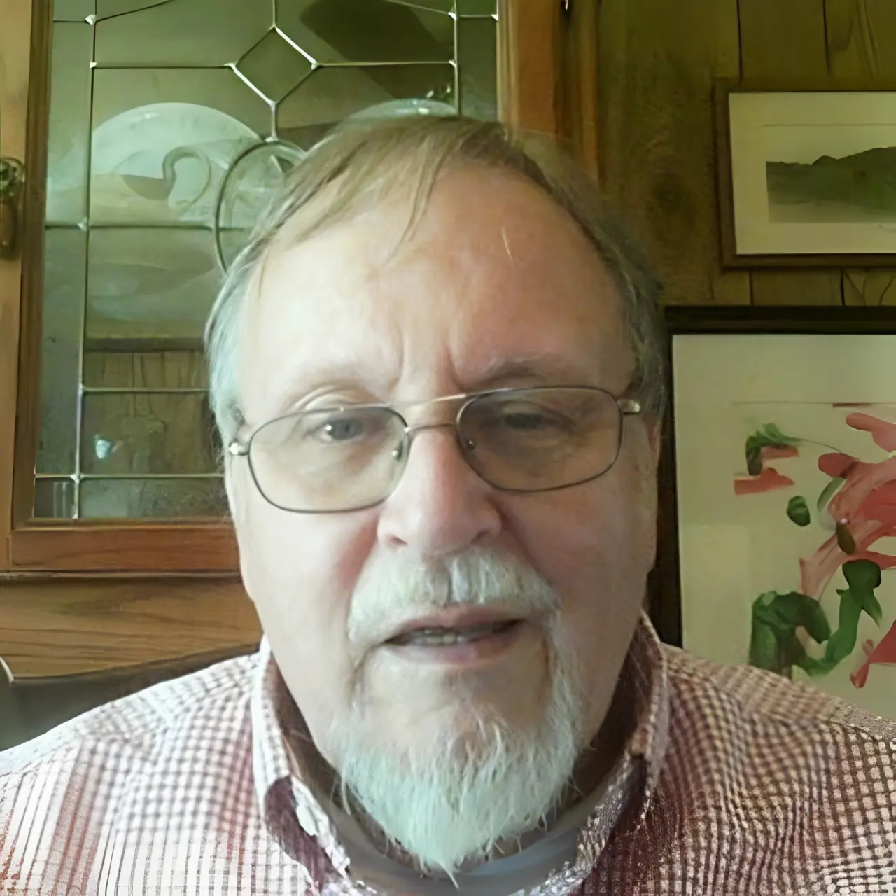 Man with glasses and beard indoors.