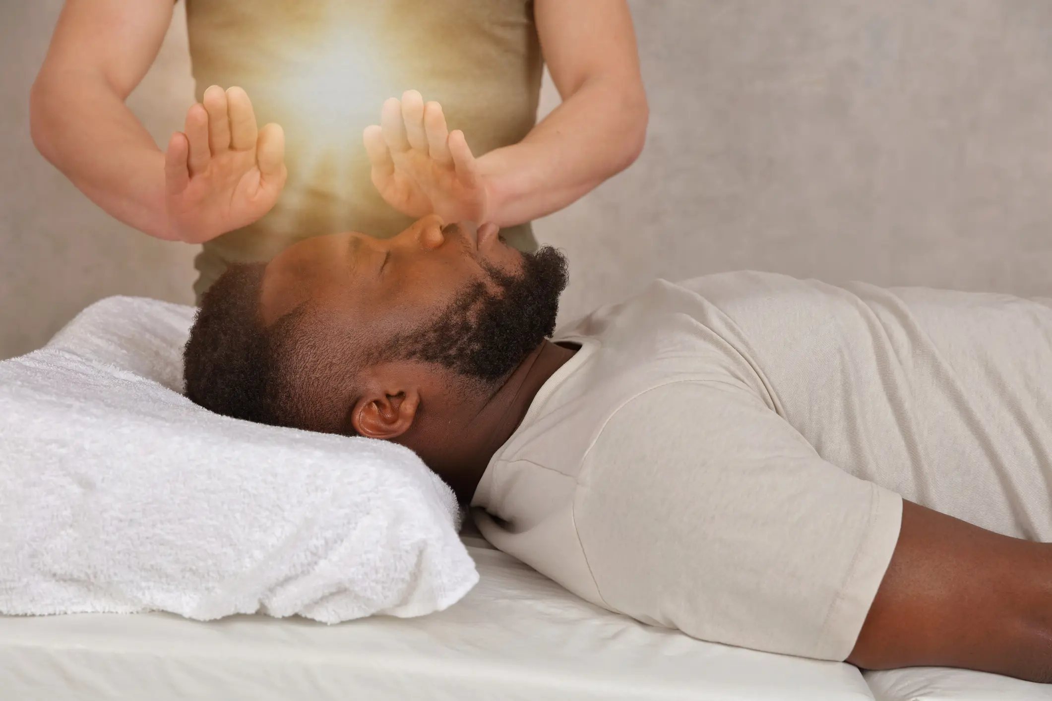 A healer channeling energy onto a man lying down with eyes closed.