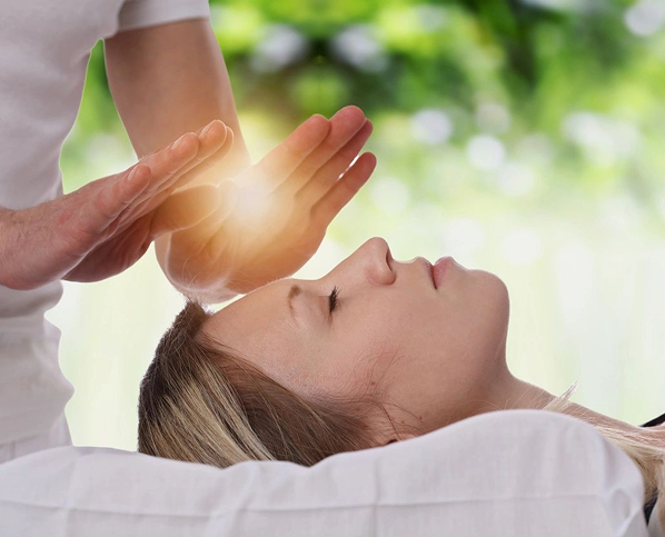 Therapist performing energy healing on a relaxed woman.