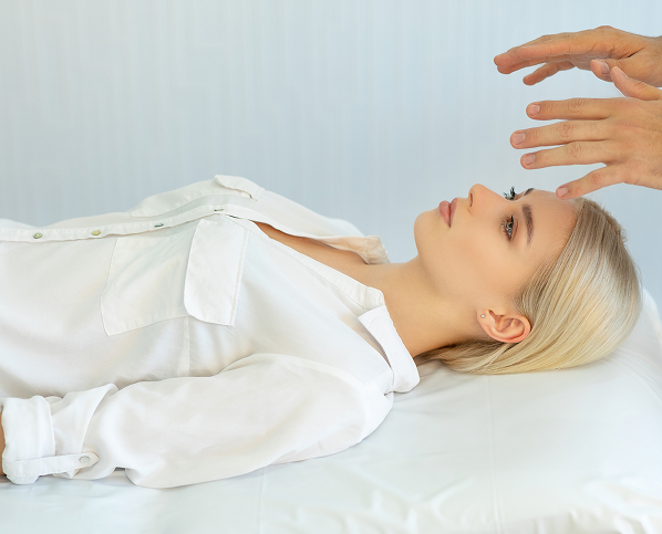 A woman lying down with a hand hovering above her forehead.