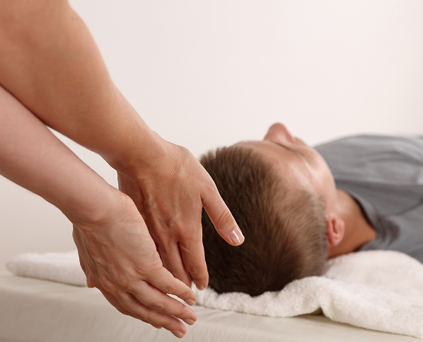 A person receiving a gentle head massage while lying down.