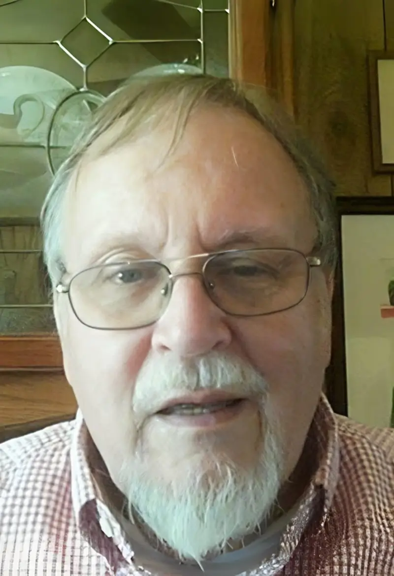 Close-up of an older man with glasses and a mustache.